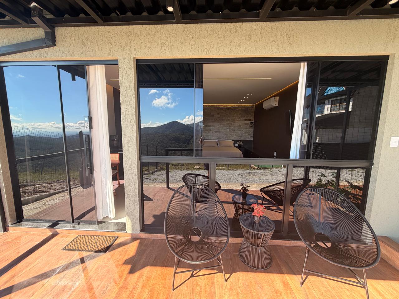 Varanda com deck de madeira e cadeiras no Loft Encanto, com vista para a serra