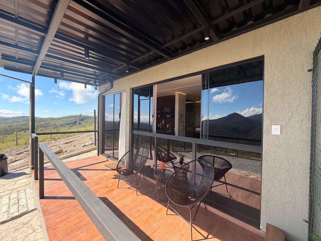 Varanda externa com cadeiras e vista para as montanhas no Loft Encanto, em Lavras Novas
